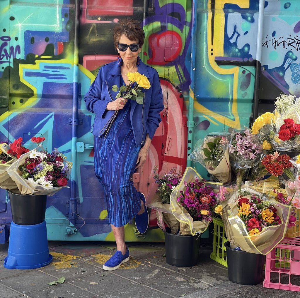 A man in blue shirt and hat standing next to table.