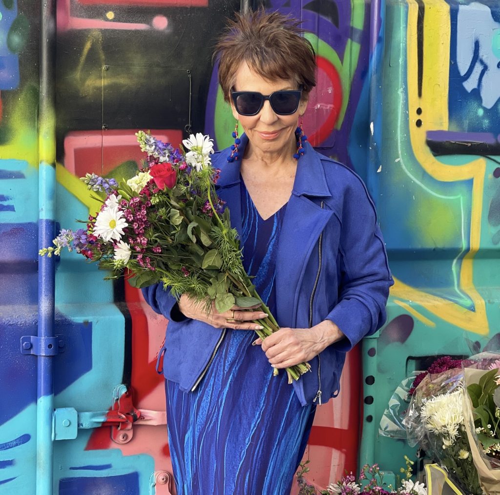 A man in blue shirt and hat standing next to table.