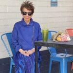 A man in blue shirt and hat standing next to table.