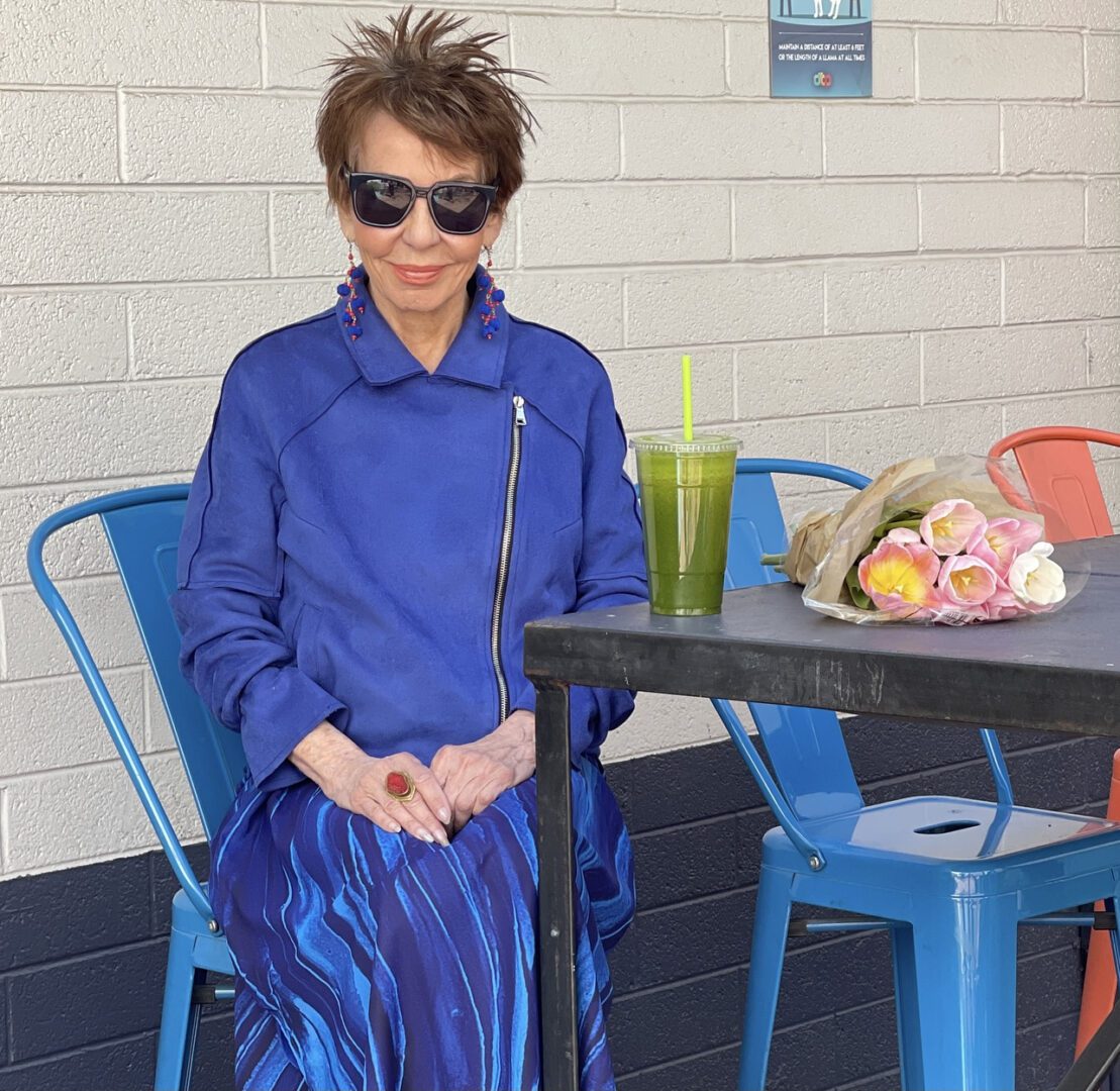 A man in blue shirt and hat standing next to table.
