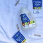 Truly free laundry detergent refillable bottle and refills with clothespins on a sheet.
