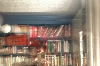 Idun St Paul with white walls, a clothing rack, perfumes, and plants in front of a large window