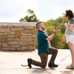 Man on one knee proposing to woman on mountain top