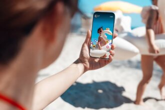A person takes a social media  photo of family playing at the beach.
