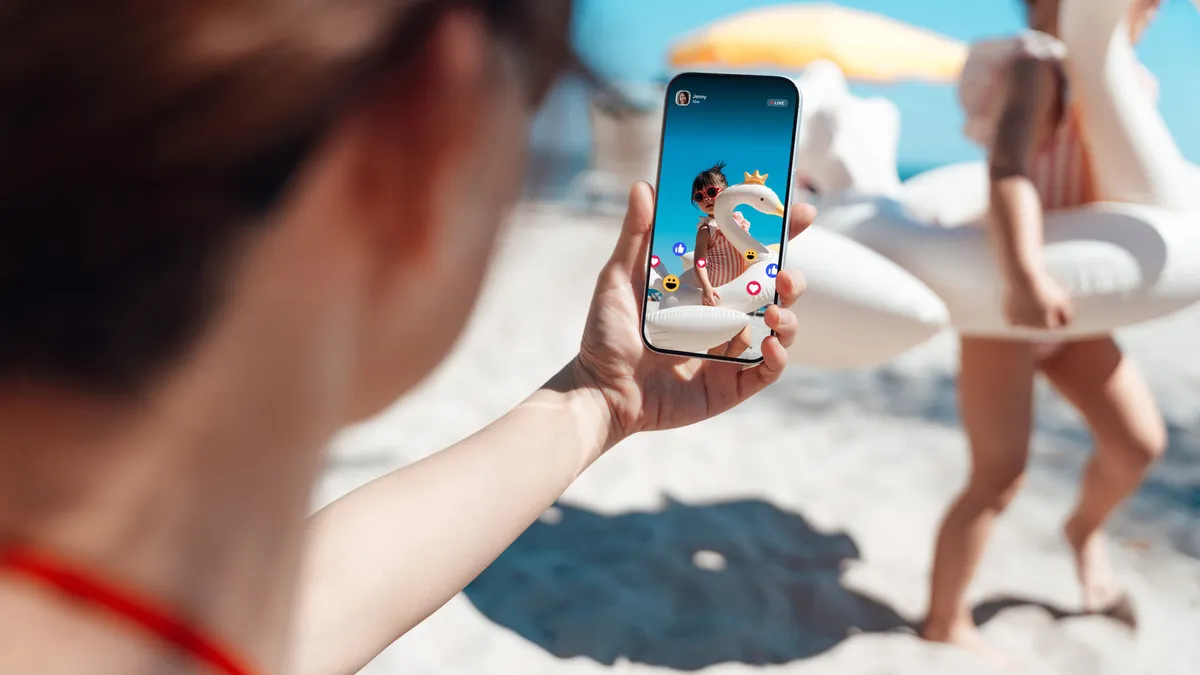 A person takes a social media  photo of family playing at the beach.